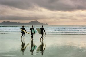 three surfers holding surfing boards